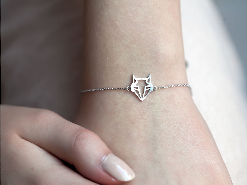 May include: A silver chain bracelet with a geometric fox pendant.