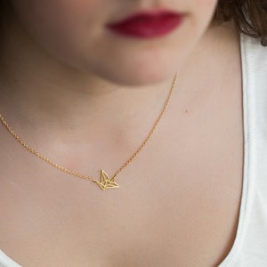 May include: A gold chain necklace with a delicate origami crane pendant.