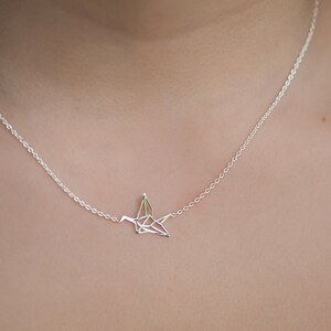 May include: A silver necklace with a delicate origami crane pendant.
