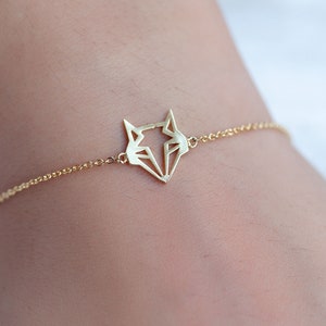 May include: A gold chain bracelet with a geometric fox pendant.