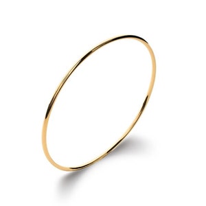 Könnte beinhalten: Ein schlichtes goldenes Armreif-Armband. Das Armband besteht aus einem dünnen, runden Draht und ist glatt und glänzend.