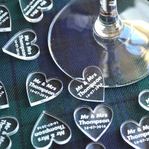 May include: Clear acrylic heart-shaped wedding favors with the text "Mr & Mrs Thompson 14-07-2016" engraved on each heart.