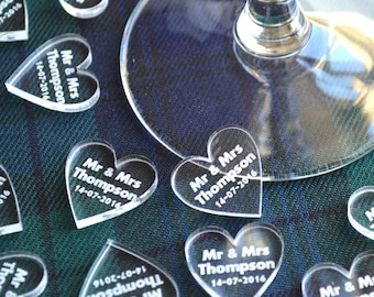 May include: Clear acrylic heart-shaped wedding favors with the text "Mr & Mrs Thompson 14-07-2016" engraved on each heart.