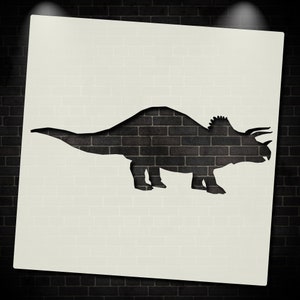 May include: A black silhouette of a triceratops dinosaur cut out of a white brick wall.