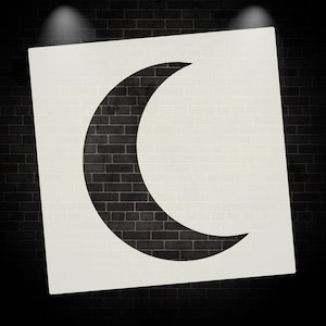 May include: A stencil featuring a crescent moon shape. The moon is black, set against a white background, and framed by a black brick wall. The image is lit by two spotlights.