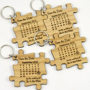 May include: Wooden puzzle piece keychains with a calendar for September 2019, engraved with "Save the Date" and "for the wedding of Mr & Mrs White." Each keychain has a silver ring.
