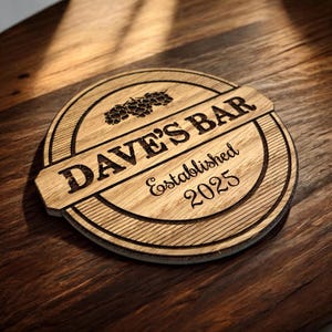 May include: A round wooden sign with the text "Dave's Bar Established 2025" and a stylized image of hops.