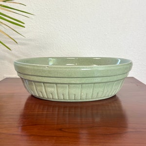 May include: A large, green ceramic bowl with a ribbed design. The bowl is glazed and has a smooth, glossy finish.