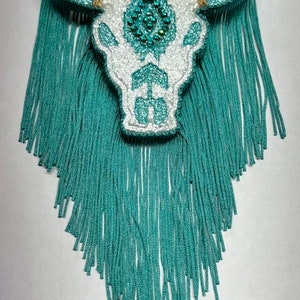 May include: White and turquoise beaded bull skull with turquoise fringe.