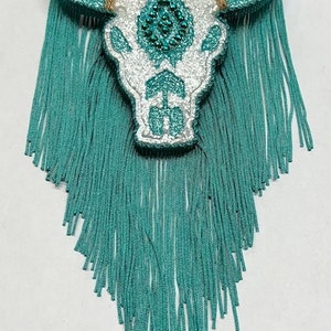 May include: White and turquoise glitter bull skull ornament with turquoise fringe.