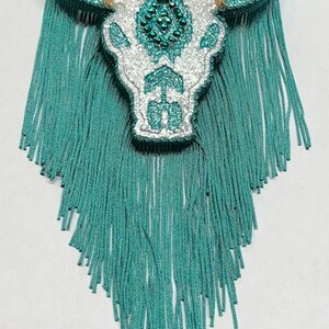 May include: White glitter bull skull with turquoise rhinestones and turquoise fringe.