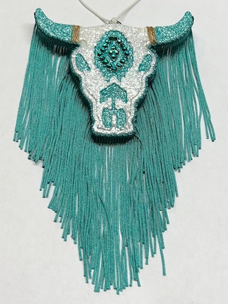 May include: White glitter bull skull with turquoise rhinestones and turquoise fringe.