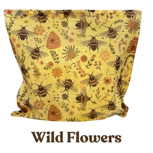 May include: A yellow fabric pouch featuring a repeating pattern of brown and black bees, orange beehives, and various small floral elements. The text "Wild Flowers" is printed in brown at the bottom of the image, centered below the fabric item.
