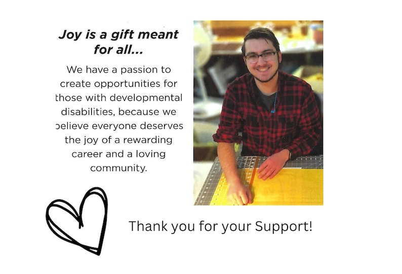 Pode incluir: Um jovem de camisa xadrez vermelha e preta sorri enquanto trabalha em um projeto artesanal. O texto "Joy is a gift meant for all..." e "Thank you for your Support!" &eacute; vis&iacute;vel na imagem.