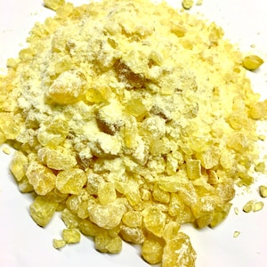 May include: A close-up of a pile of yellow resin crystals, some of which are coated in a white powder.