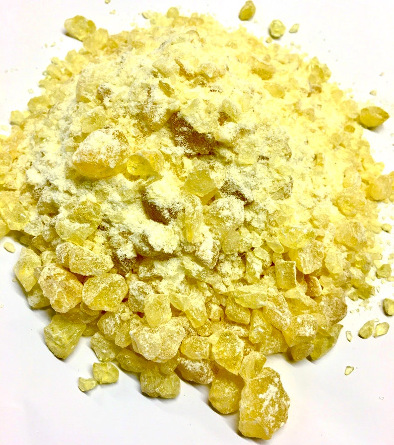May include: A close-up of a pile of yellow resin crystals, some of which are coated in a white powder.