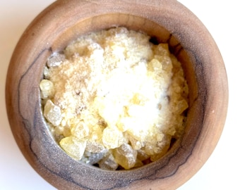 May include: A wooden mortar and pestle with a white powder and yellow resin inside.