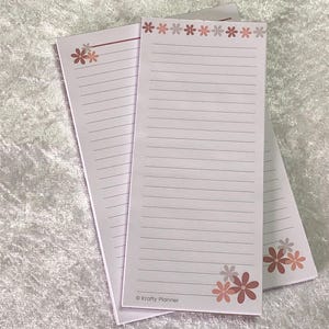 May include: Three lined notepads with a floral design in shades of pink and brown. The notepads have a floral border at the top and bottom, and the text "© Krafty Planner" is printed at the bottom of the notepad.