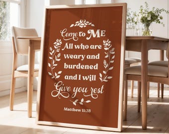 May include: A framed print with the text "Come to ME All who are weary and burdened and I will Give you rest Matthew 11:28" in white script on a brown background. The print is leaning against a wall in a dining room.