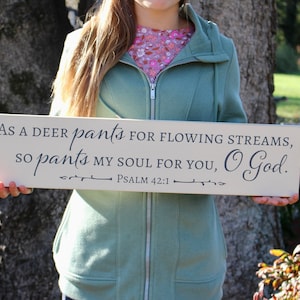 May include: A white wooden sign with the text "AS A DEER pants FOR FLOWING STREAMS, SO pants MY SOUL FOR YOU, O God. PSALM 42:1" in black lettering.