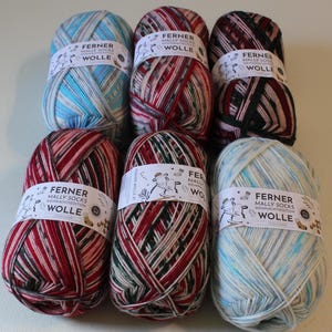 May include: Six balls of yarn in various colors, including red, green, blue, and white. Each ball has a label that reads "Ferner Mally Socks Weihnachts Edition Wolle".