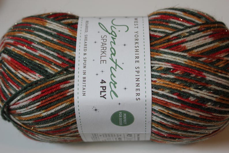 May include: A ball of Signature Sparkle 4 Ply yarn from West Yorkshire Spinners. The yarn is a mix of red, green, gold, and white with a sparkly finish. The label reads "Perfect for Socks."