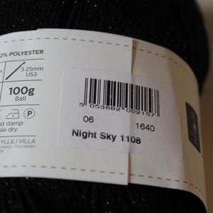 May include: A close-up of a black yarn ball with a label. The label indicates the yarn is Night Sky 1108, 100g, and 400 meters. It also specifies the needle size as 3.25mm, US3.