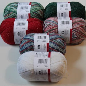 May include: A collection of six yarn skeins in various colors, including green, red, and white, with metallic threads. Each skein has a label with a barcode and product information. The yarns are arranged in a slightly overlapping pattern.