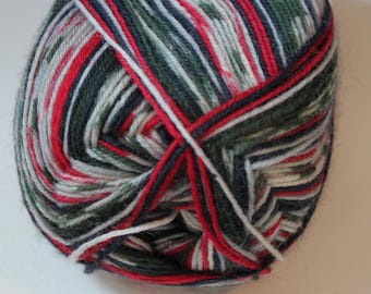 May include: A close-up of a ball of yarn with a mix of colors, including red, green, white, and navy blue. The yarn is tightly wound, showing the different colored strands intertwined. Ideal for knitting and crochet projects.