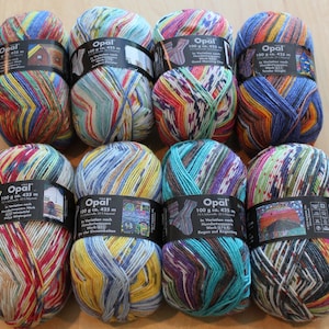 May include: A collection of Opal brand yarn skeins. The yarn is multicolored with shades of blue, yellow, red, and green. Each skein is labeled with the brand name, weight, and length. The yarn is suitable for knitting and crochet projects.