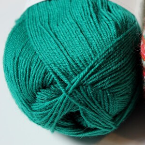 May include: Close-up of a ball of teal green yarn. The yarn is tightly wound, showing the individual strands. The label at the top indicates it is 4-ply yarn. The yarn is a solid, vibrant color, suitable for knitting or crocheting projects.