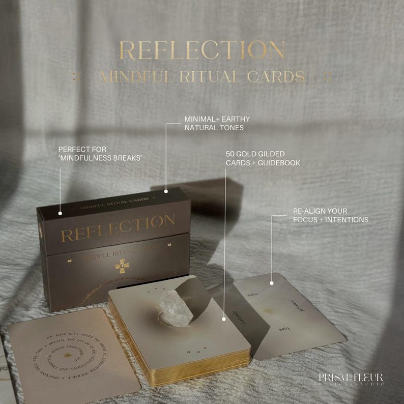 Op de afbeelding: Een set Reflection Mindful Ritual Cards in een donkerbruine doos met gouden letters. De set bevat 50 kaarten met gouden randen en een gids. De kaarten hebben aardse tinten en minimalistische ontwerpen met tekst over mindfulness en intenties.