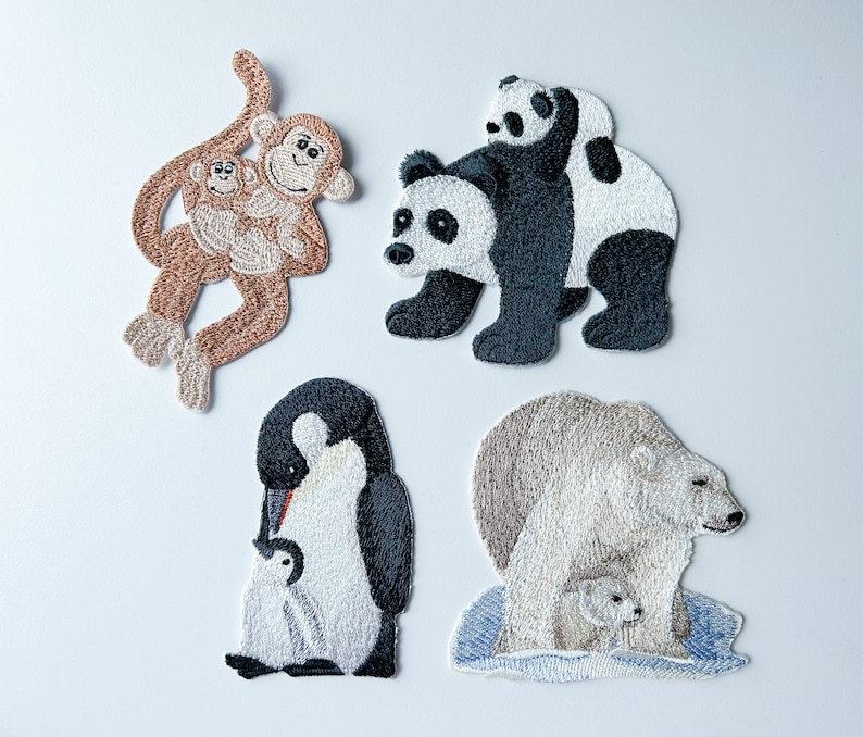 May include: Five embroidered iron-on patches featuring different animals. The patches include a brown monkey with a baby monkey, a black and white panda with a baby panda, a black and white penguin with a baby penguin, and a white polar bear with a baby polar bear.