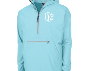 May include: A light blue anorak jacket with a hood and a quarter-zip closure. The jacket features a white monogram on the chest and a front pocket with a zipper. The jacket has a drawstring at the hood and the bottom hem.
