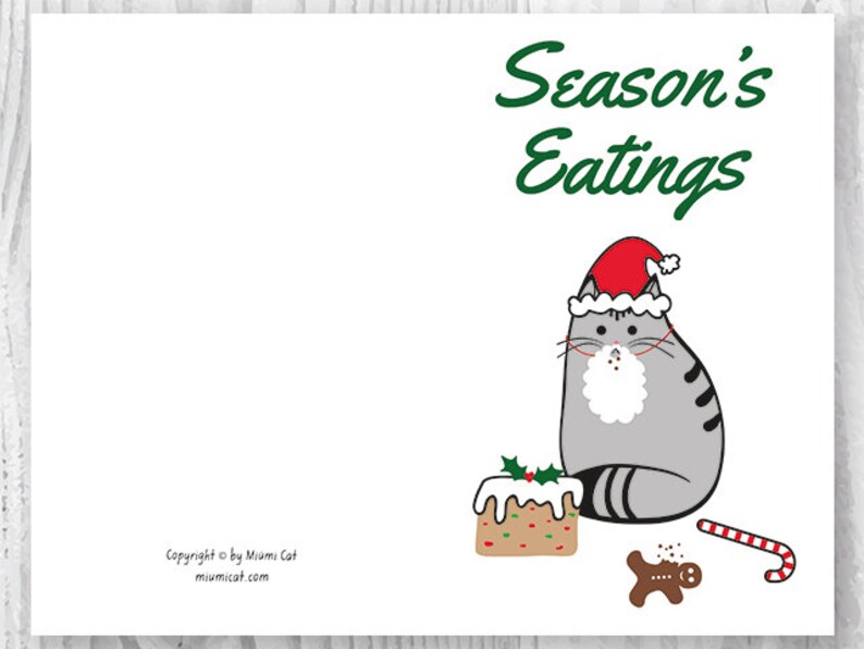 May include: A gray cat wearing a red Santa hat sits next to a gingerbread man and a decorated cake. The text "Season's Eatings" is written in green above the cat.