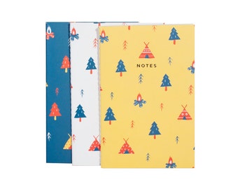 May include: Three notebooks with camping-themed patterns. The covers feature illustrations of teepees, campfires, and trees in blue, white, and yellow. The yellow notebook has the word "NOTES" printed on it.
