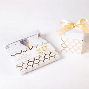 May include: White gift boxes with a gold geometric pattern. One box is open with a gold ribbon. A set of five boxes is packaged in a clear plastic container. The packaging includes the text "colorworks SET OF 5 GIFT BOXES".