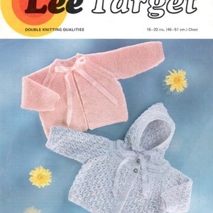 May include: Two knitted baby sweaters, one pink and one light blue, with a hood. The sweaters are laid out on a blue background with yellow flowers.