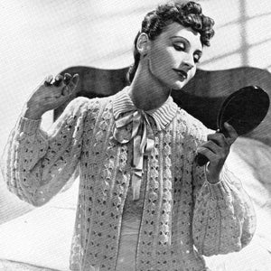 Peut inclure: Une photo en noir et blanc d'une femme portant une veste de lit en crochet avec un motif en point de coquille. La veste a un col et un nœud papillon. Le texte sur l'image est "Weldons Leaflet 3d No. 300 Sweet Bed-Jacket In a Dainty Shell Pattern 9 ozs. of 3-ply."