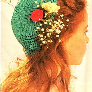 May include: A young girl with long, red hair wearing a teal crocheted hat with white and red flowers.