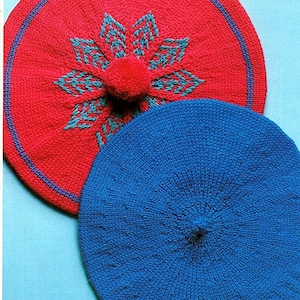 May include: Two knitted berets, one red with a blue flower design and a pom-pom, and one blue.