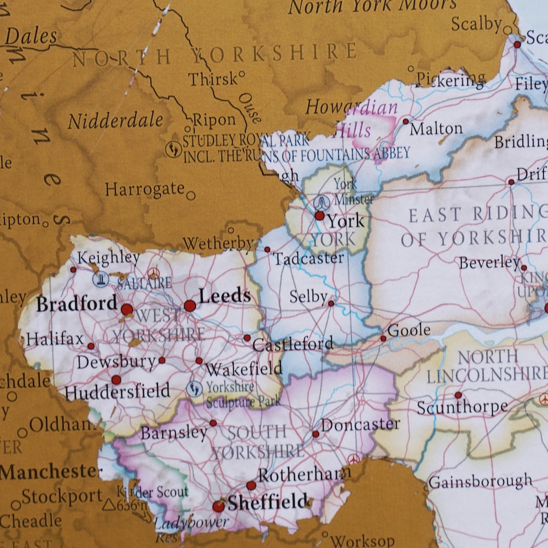 May include: A map of Yorkshire, England, highlighting the major cities and towns. The map is in a vintage style with a gold background and white lines. The cities and towns are labeled in black text.