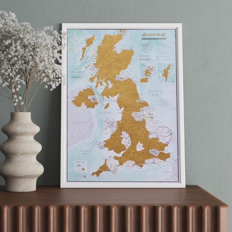 May include: A white framed scratch-off map of the United Kingdom with gold foil covering the map. The map is titled "Scratch U.K."