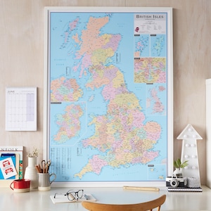 May include: A framed map of the British Isles with a light blue background and colorful borders for each region. The map includes a key with different colored dots representing different types of locations. The map is hanging on a light wood wall.