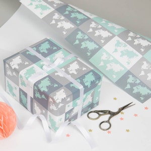 May include: A gift wrapped in blue and green wrapping paper with a world map pattern. The paper is wrapped around a box with a white ribbon. There are gold stars scattered on the surface.