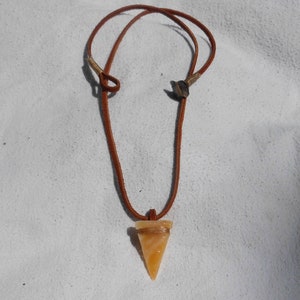 May include: A brown leather cord necklace with a triangular orange agate pendant.