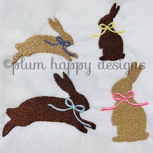 May include: Four embroidered bunny silhouettes with different colored bows. The bunnies are brown and gold, and the bows are pink, blue, yellow, and light blue.