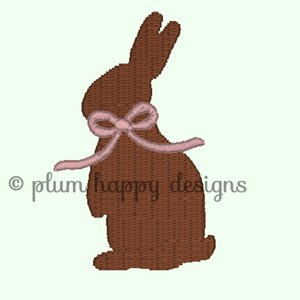 May include: A brown chocolate bunny with a pink bow. The bunny is standing on a white background.