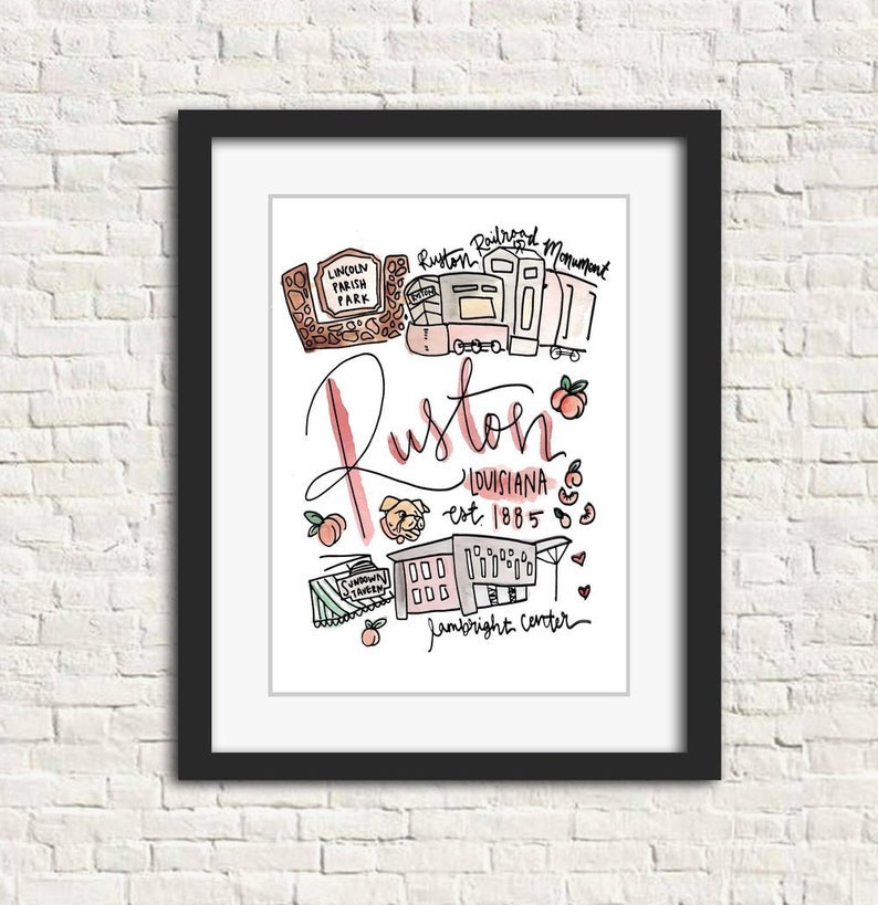 May include: A framed art print featuring a hand-drawn illustration of Ruston, Louisiana. The artwork includes the text "Ruston, Louisiana est. 1885" and various local landmarks, all in a colorful, whimsical style. The print is set against a white background.