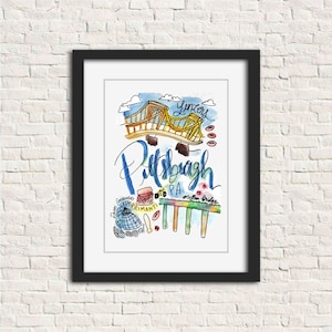 May include: A framed watercolor print featuring a colorful illustration of Pittsburgh, PA. The artwork includes the city's name in cursive, a bridge, and other iconic landmarks. The print is in a black frame and hangs on a white brick wall.